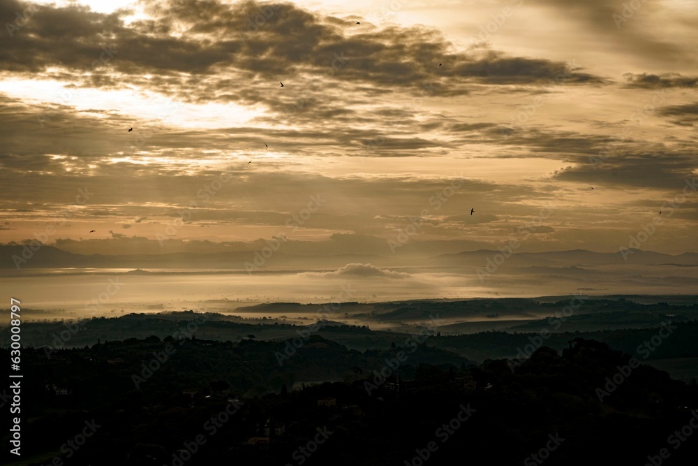 Tranquil landscape featuring a stunning golden sunset over rolling hills