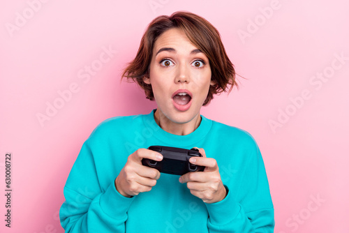 Photo of impressed crazy young lady hands hold controller open mouth playing video games isolated on pink color background
