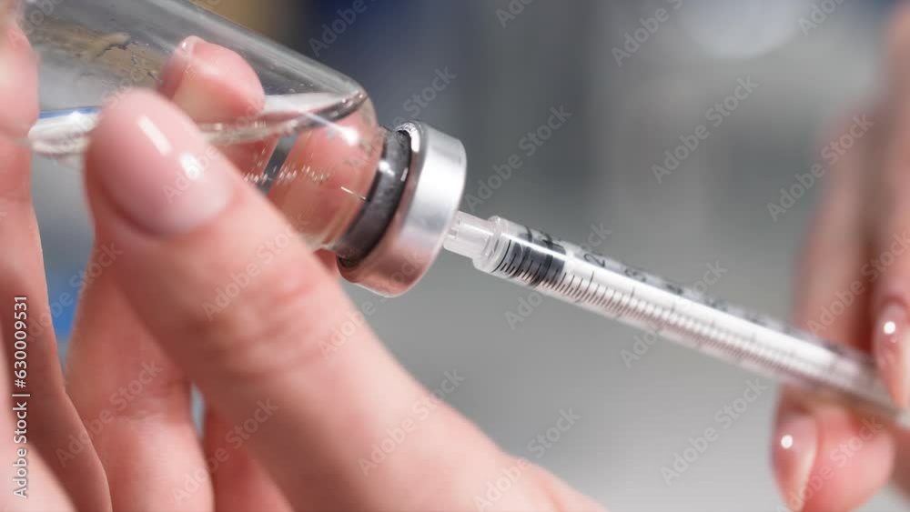 injections, young woman draws medicine from a bottle with a syringe with needle, close-up injections, young woman draws medicine from a bottle with a syringe with needle, close-up