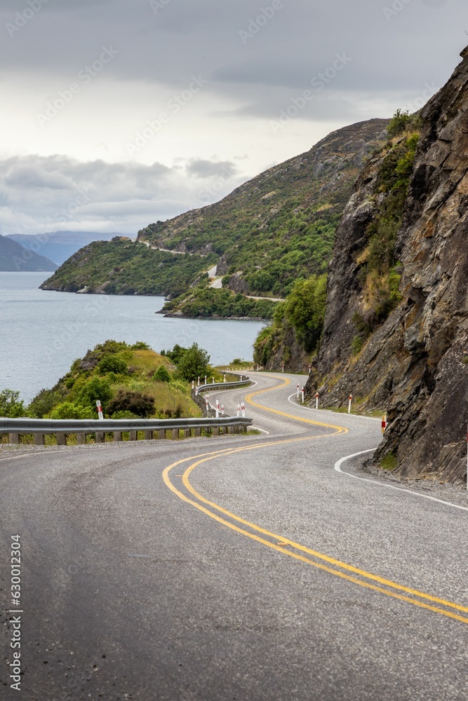 Winding mountain road lies in the foreground of a breathtaking landscape in Queenstown, New Zealand Winding mountain road lies in the foreground of a breathtaking landscape in Queenstown, New Zealand