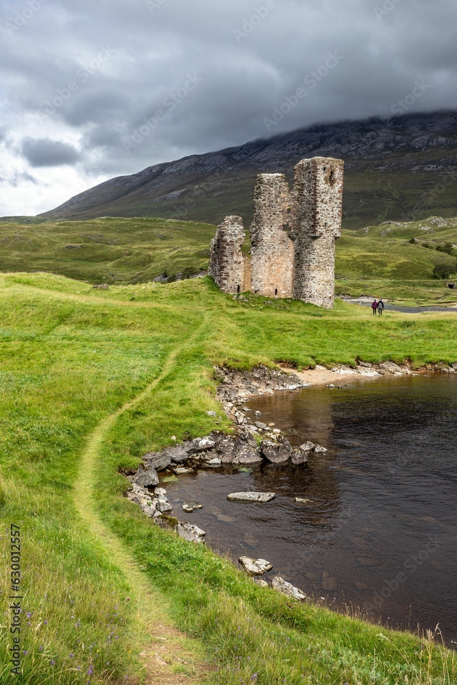Ancient Ardvreck Castle ruin located on the edge of a tranquil lake in Scotland