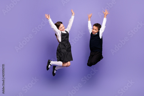 Photo of positive schoolkids jumping with raised hands up enjoying academic class courses isolated bright color background