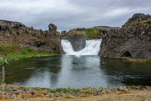 Picturesque landscape of a majestic Hjalparfoss waterfall cascading down a rocky cliff