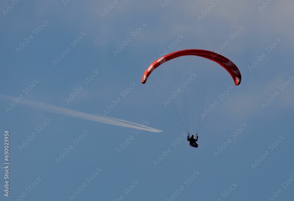 a person on a parasail, going under clouds a person on a parasail, going under clouds