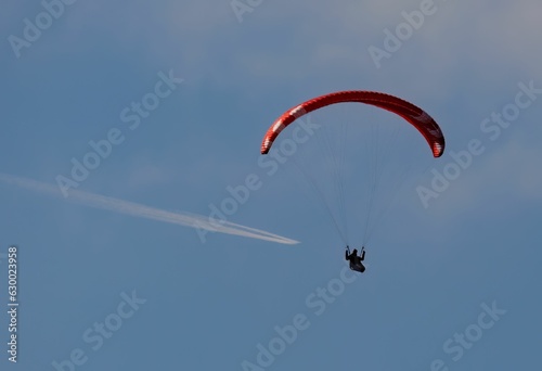 a person on a parasail, going under clouds