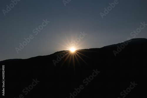 Scenic view of sun setting behind a mountain range