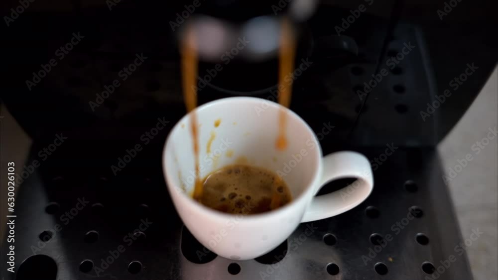 Coffee machine pouring arabica into a white espresso cup, slow motion, vertical screen