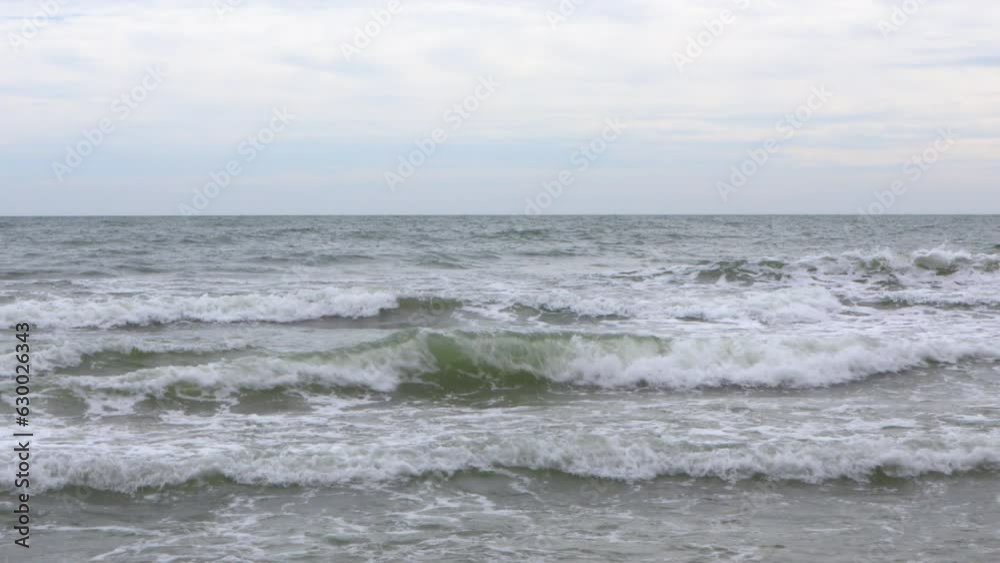 Sea waves blow on the sea beach on a windy day. The sea when the weather is sunny. The waves hitting the empty sandy beach. Sea waves blow on the sea beach on a windy day. The sea when the weather is sunny. The waves hitting the empty sandy beach.