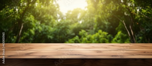 A wooden table with a blank surface is placed against a blurry natural background. This space can be