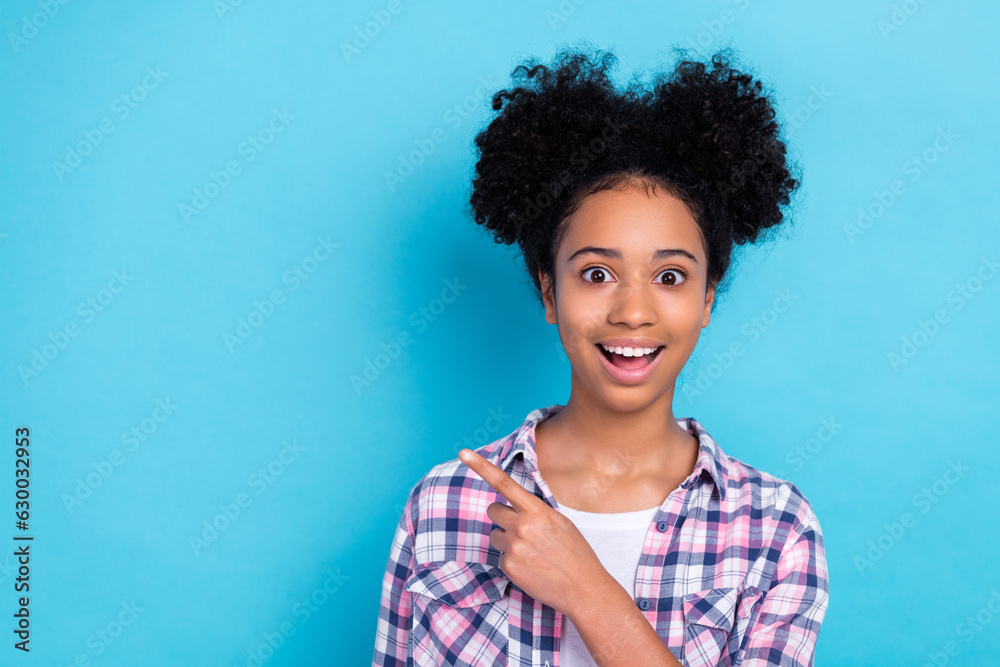 Photo of impressed overjoyed girl dressed checkered shirt indicating empty space sale astonished staring isolated on blue color background Photo of impressed overjoyed girl dressed checkered shirt indicating empty space sale astonished staring isolated on blue color background