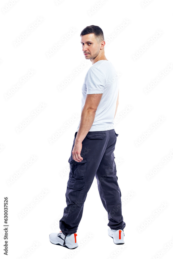 A smiling man is standing in a white tank top and blue casual trousers. Positivity and success. Isolated on a white background. Vertical. Back view.