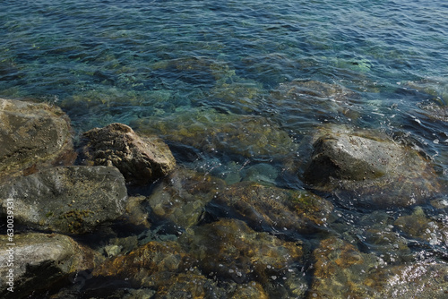 Cinque Terre, Italy - close-up of rocks in the water at a rugged beach in Riomaggiore, a seaside town in the Italian Riviera. Summer travel vacation background. Postcard from Europe.