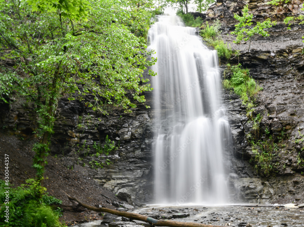 Natural waterfall along the hiking path in the forest woods