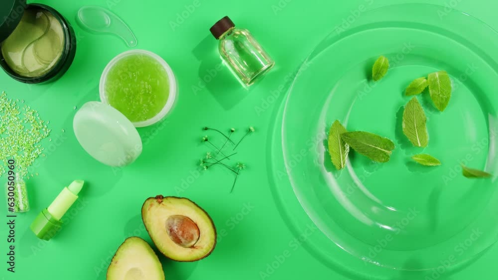 Fresh ripe avocados with cream and essential oil on green background with mint mentol, make up cosmetics Fresh ripe avocados with cream and essential oil on green background with mint mentol, make up cosmetics