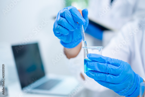 Close up of female scientist or researcher is droping blue substance or liquid into sample test tube. Concept of science, biochemistry, chemical laboratory. Substance study analyzing experiment