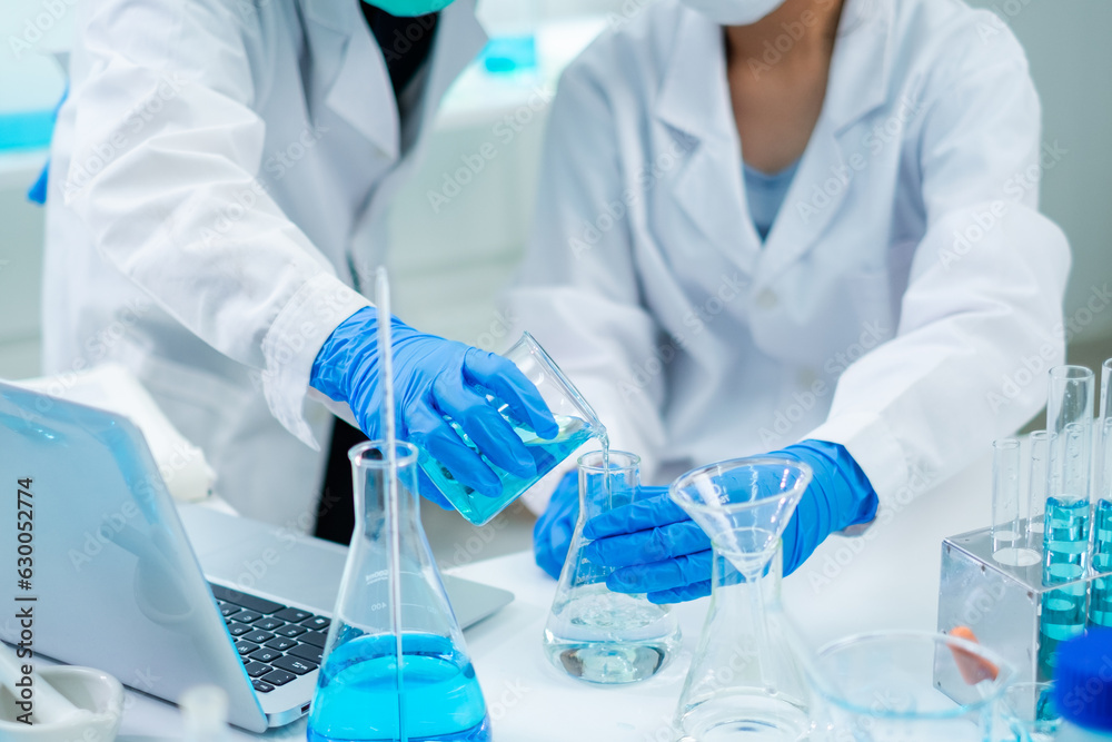 Fototapeta premium Close up of Female scientist or researcher is pouring substance or liquid in to a sample test tube. Concept of science, biochemistry, chemical, biotechnology laboratory. Analyzing and experiment