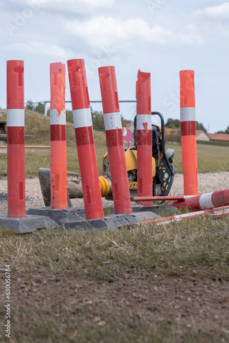 Used plastic roadwork markers at fiber connection digging site with heavy indsutrial power tools on the side.