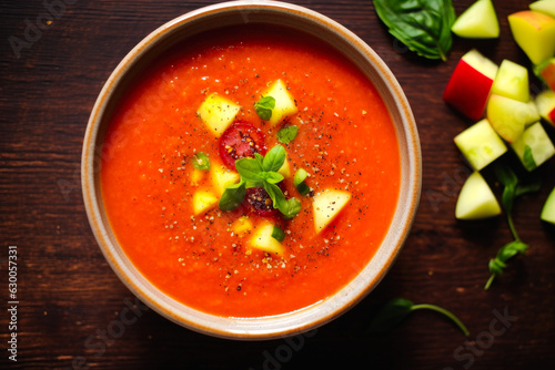 Tomato gazpacho soup with pepper and garlic, Spanish cuisine food. Top down view on a dark bacground