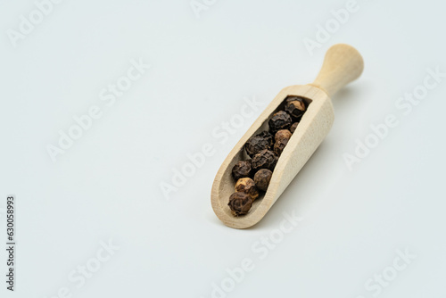 The round black pepper is placed in a small wooden spoon