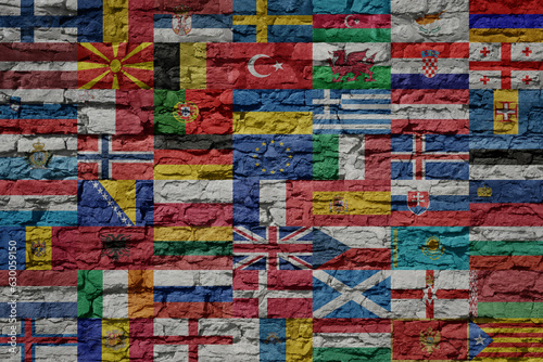 all colorful painted national european flags on a massive big old brick wall. © luzitanija