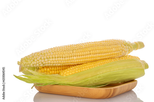 Several ears of sweet corn on a bamboo plate, close-up, on a white background.