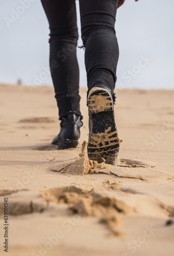Obraz na płótnie footprints in the sand, in black boots and brown coat, walking in the dunes. w salonie