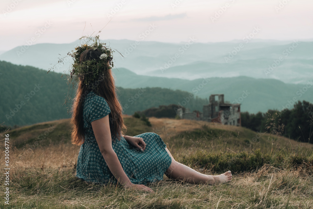 Φωτογραφία A girl in a wreath of flowers enjoys the sunset in the mountains