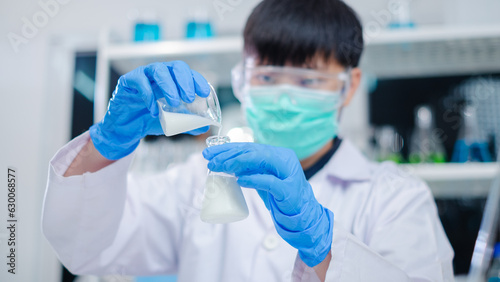 Nutritionist or scientist is pouring and holding a bottle of sample milk. Concept of nutrition, lactose, protein, bacteria, fat and glucose laboratory. Dairy milk test, research or analysis product.