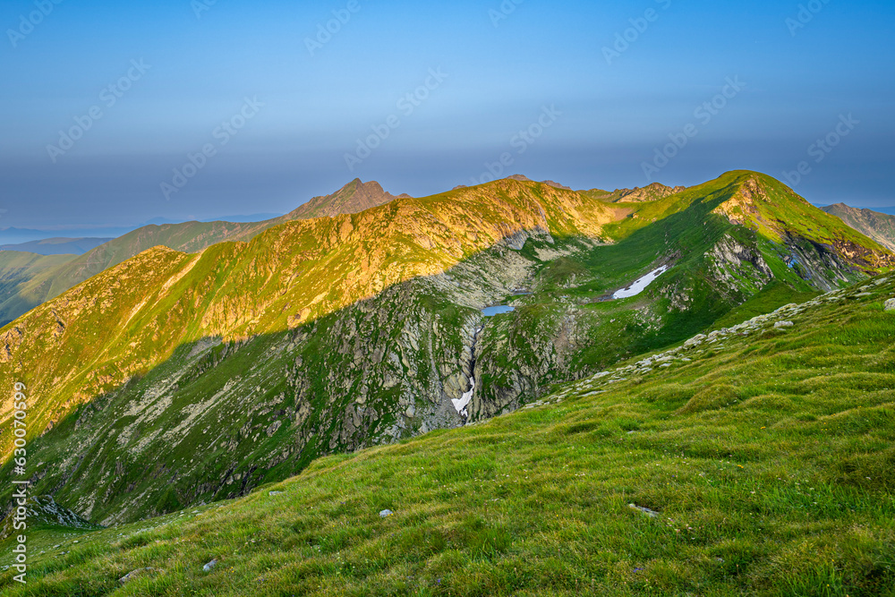 Obraz premium The Fagaras Mountains at sunrise. A view on the Mount Paltinul from the Iezerul Caprei, Carpathians, Romania.