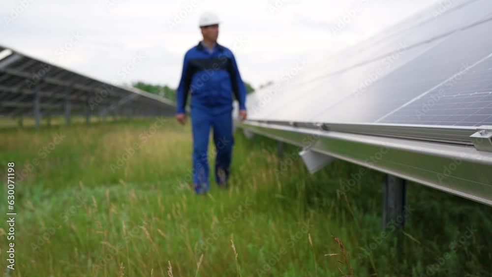 Service Engineer or electrician goes by solar panels, working and solving problem for green energy solar power plant operation. Technician maintenance solar cells on Solar Energy Plant Service Engineer or electrician goes by solar panels, working and solving problem for green energy solar power plant operation. Technician maintenance solar cells on Solar Energy Plant