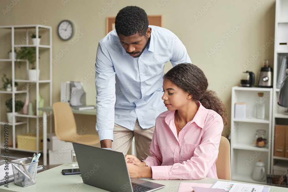 Portrait of manager assisting young employee with project in office, copy space Portrait of manager assisting young employee with project in office, copy space