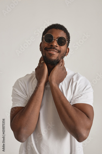 Minimal portrait of African American man with sunglasses posing in studio against white