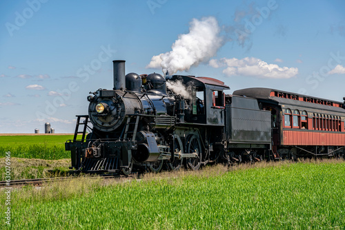 A View of An Approaching Antique Restored Steam Passenger Train,, Blowing Smoke and Traveling Thru Farmlands on a Sunny Spring Day