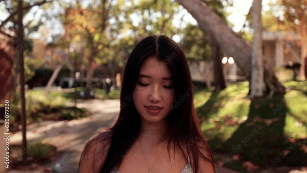 Cute Asian female college student walking toward the camera.