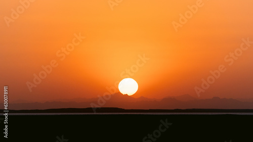 Epic sunset landscape sky with big bright sun going behind the mountains in Egypt.