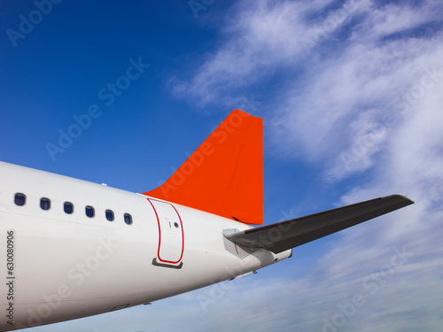 Red-tailed plane. The rear of the passenger plane, detail from the stern, a red tail and an azure cloudy sky. An airplane photo taken from the bottom. vibrant colors