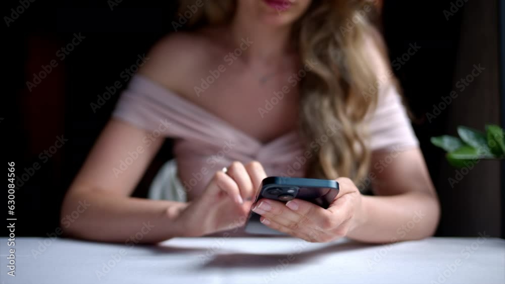 Woman working on blue mobile phone at a restaurant Woman working on blue mobile phone at a restaurant