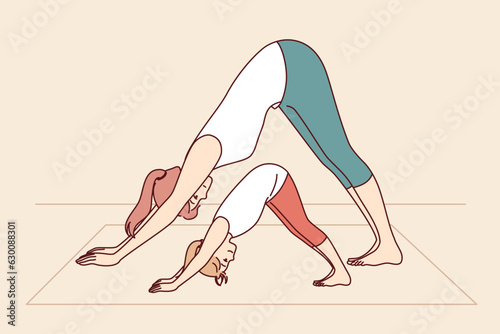 Mother and daughter are engaged in yoga and exercises, leading healthy lifestyle and learning good habits that improve well-being. Woman with little girl doing yoga pose adho mukha svanasana together