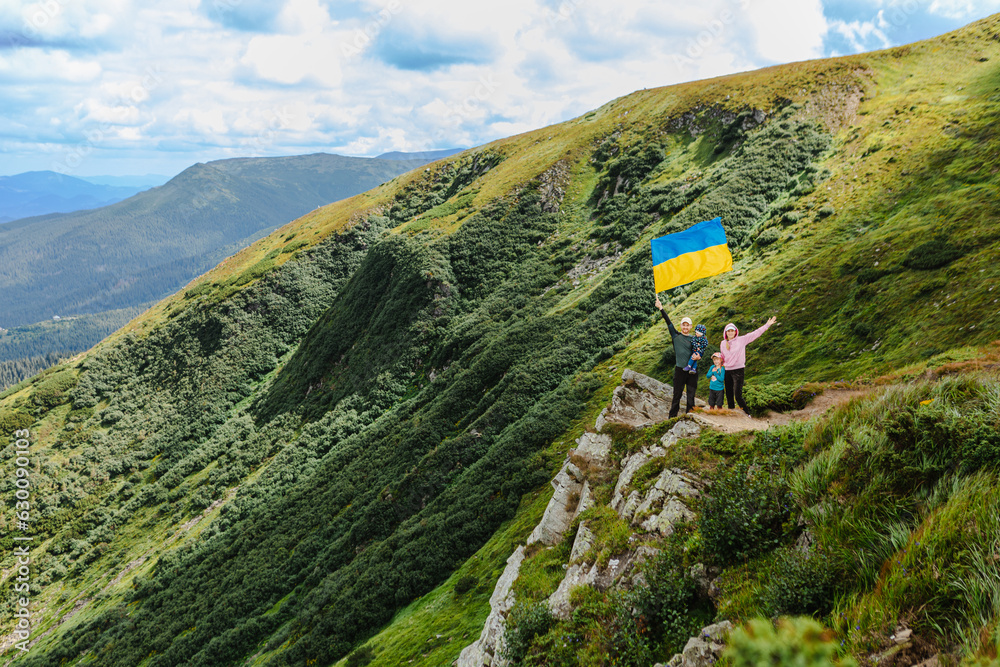 A family on top of a mountain with a ukrainian flag