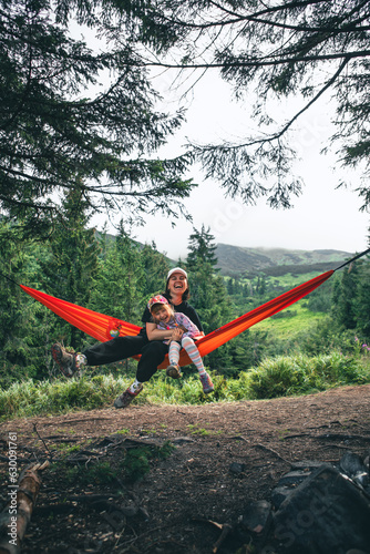woman with girl kid on hammock mountains on background