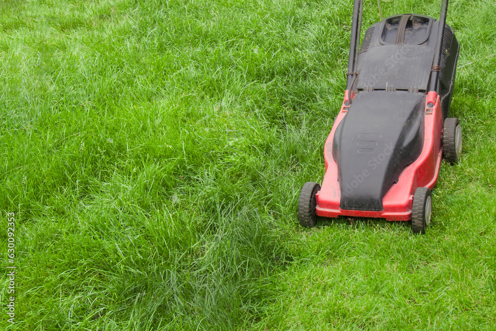 red lawn mower on a green manicured lawn, mowed lawn not mowed lawn, lawn mowing, space for text, free space, open space red lawn mower on a green manicured lawn, mowed lawn not mowed lawn, lawn mowing, space for text, free space, open space