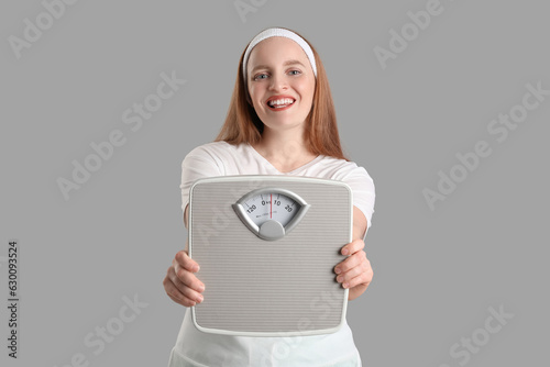 Young overweight woman with scales on grey background