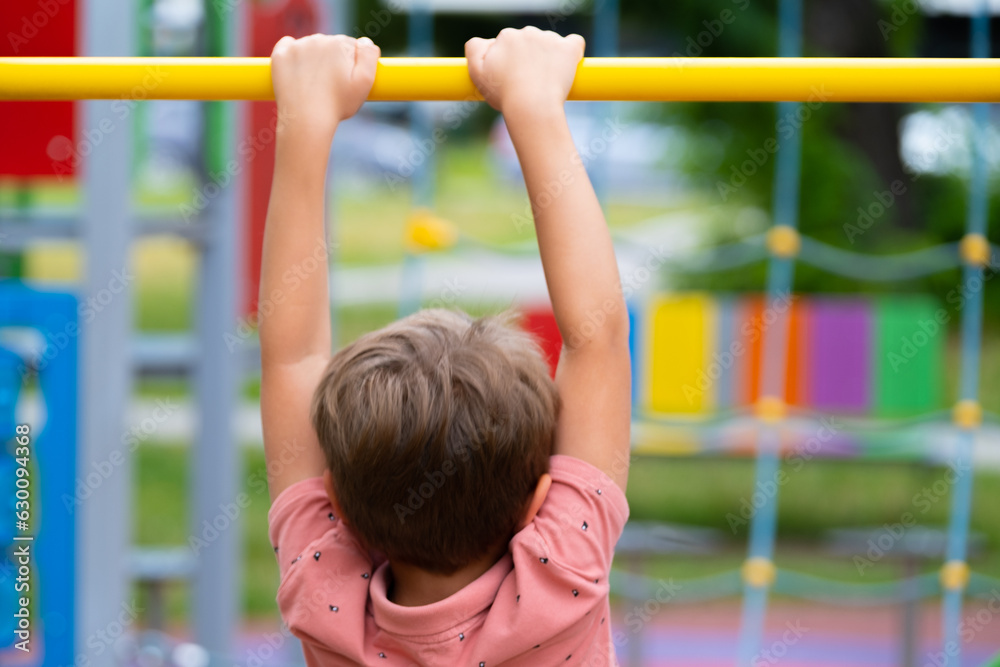 Boy playing sports on street sports ground. Boy pulling himself up on horizontal bar.. Boy playing sports on street sports ground. Boy pulling himself up on horizontal bar..