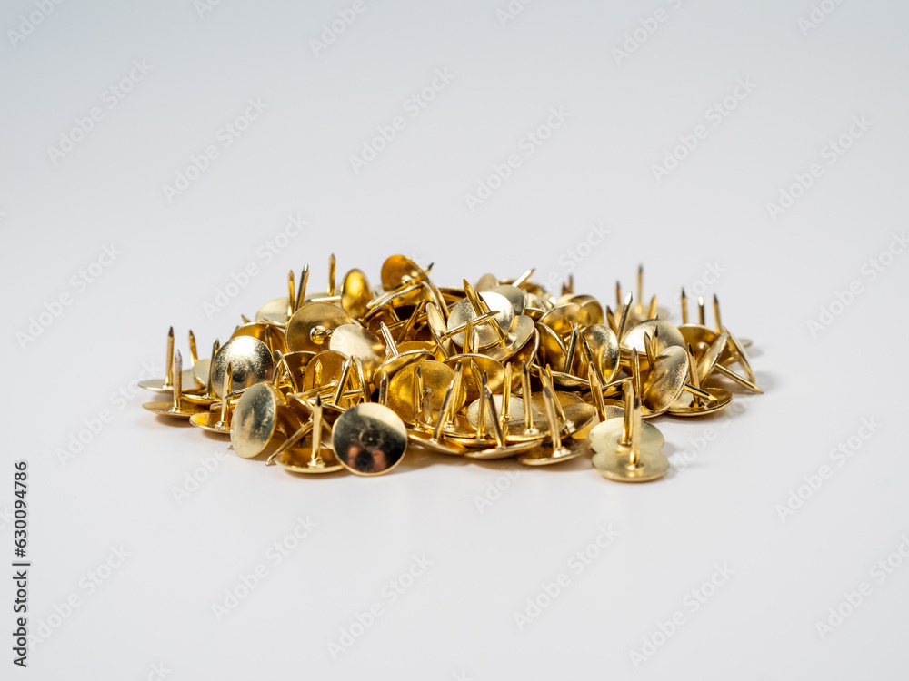 Pushpins of gold color on a white background. Push pins close up.