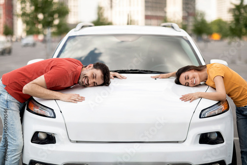 Happy young couple hugging their brand new white car