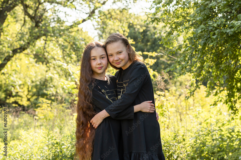 Two Real Children, Siblings Hug, Green Trees, Park on Background. Best Friends, Love. Joyful Girls Spend Time in Nature. Lifestyle, Carefree Childhood. Horizontal Plane Two Real Children, Siblings Hug, Green Trees, Park on Background. Best Friends, Love. Joyful Girls Spend Time in Nature. Lifestyle, Carefree Childhood. Horizontal Plane