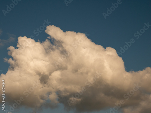 Single fluffy cloud over sunset sky background. Fluffy cumulus cloud shape photo