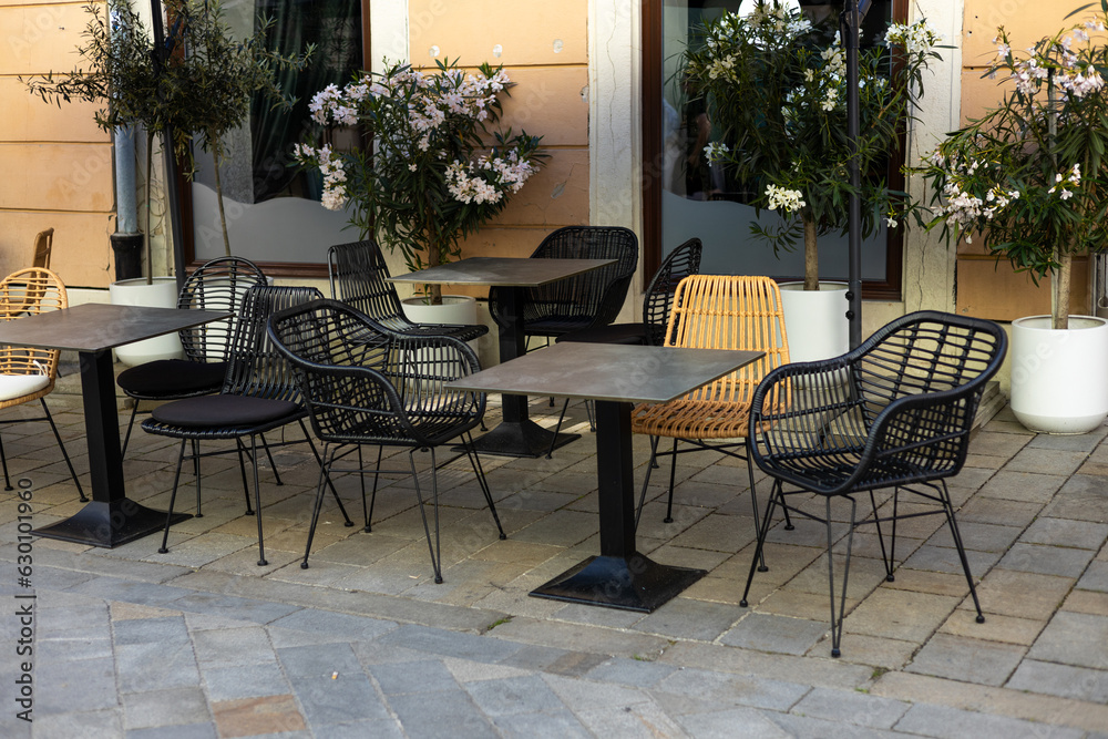 Empty restaurant summer terrace with tables and chairs. Reastaurant tables waiting for customers at an outdoor terrace, hipster style