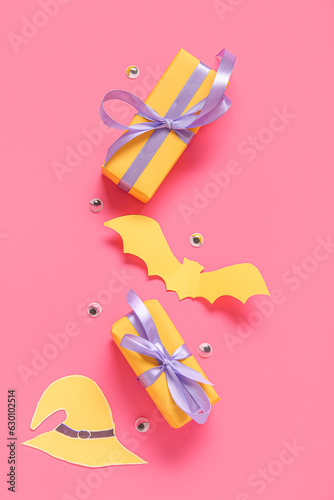 Composition with beautiful gift boxes and Halloween decor on pink background
