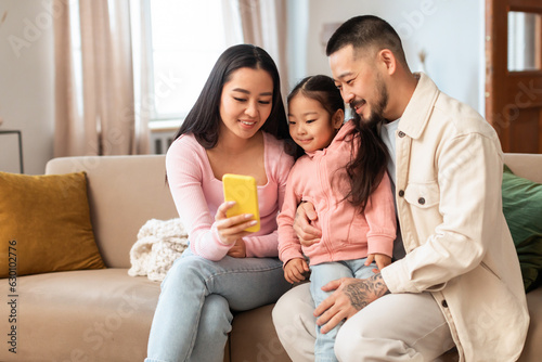 Korean family using mobile phone enjoying watching videos at home